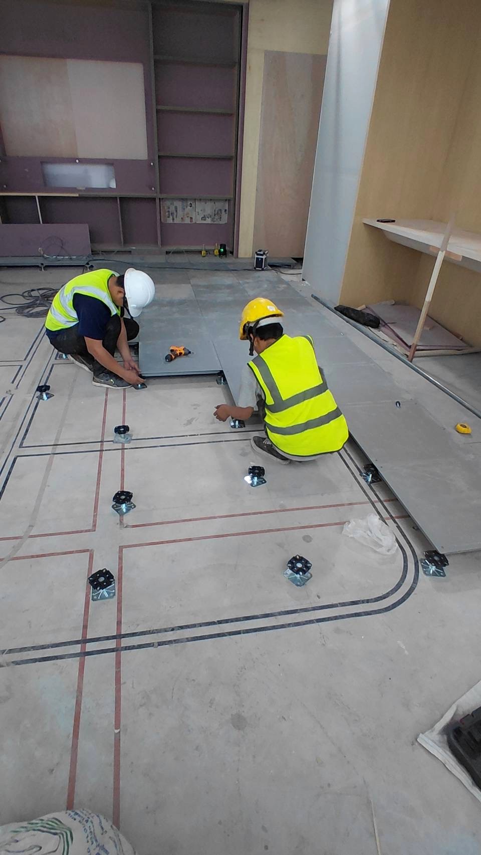 ช่างติดตั้งแผ่นพื้นยก Rhino บนขารองรับ (raised floor panels on pedestals)